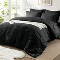 Black textured comforter set on a bed in a bright bedroom with natural light.